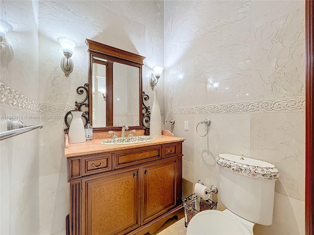 bathroom featuring vanity, tile walls, and toilet