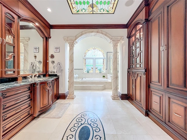 bathroom featuring decorative columns, vanity, a relaxing tiled tub, and ornamental molding