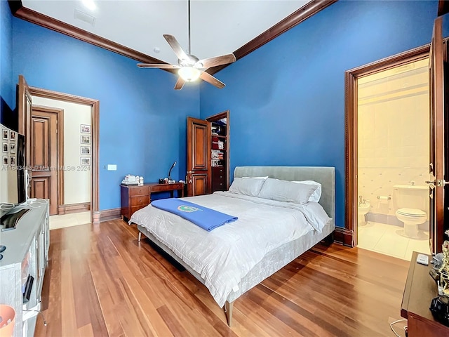 bedroom featuring hardwood / wood-style flooring, ensuite bath, ceiling fan, and ornamental molding