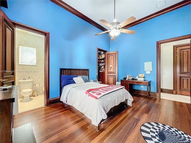 bedroom with ceiling fan, crown molding, dark wood-type flooring, and connected bathroom