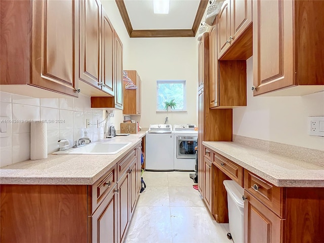 kitchen with decorative backsplash, crown molding, washer and clothes dryer, and sink