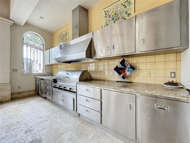 kitchen with wall chimney range hood, sink, a textured ceiling, tasteful backsplash, and light stone counters