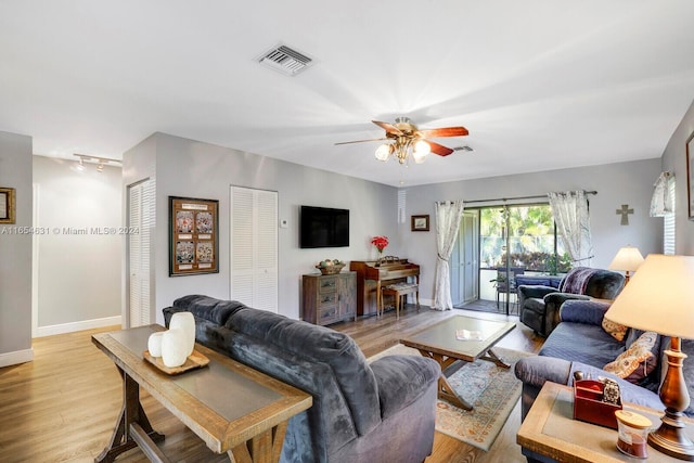 living room featuring ceiling fan, rail lighting, and light hardwood / wood-style flooring