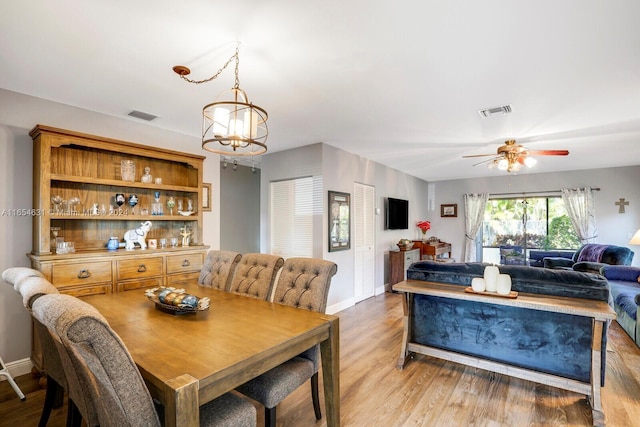 dining space with light hardwood / wood-style floors and ceiling fan with notable chandelier