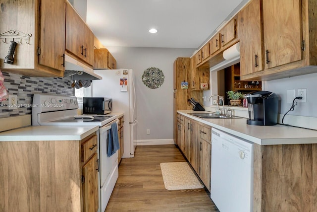 kitchen with light wood-type flooring, white appliances, sink, and backsplash