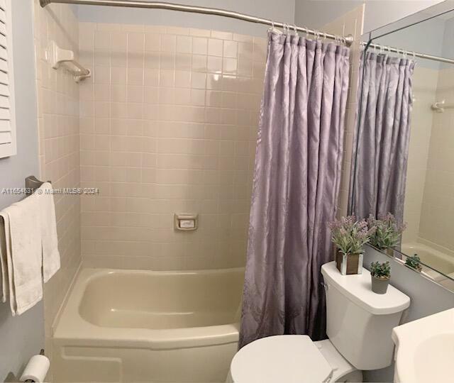 bathroom with shower / bath combo with shower curtain and toilet