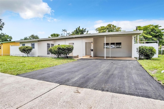 ranch-style home featuring a carport and a front lawn