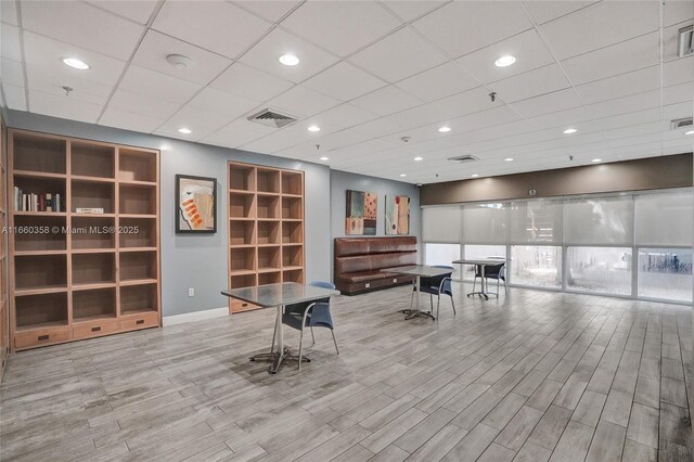 interior space with a paneled ceiling and light wood-type flooring