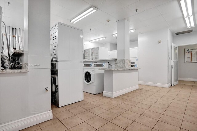 washroom with stacked washer / drying machine and light tile patterned floors