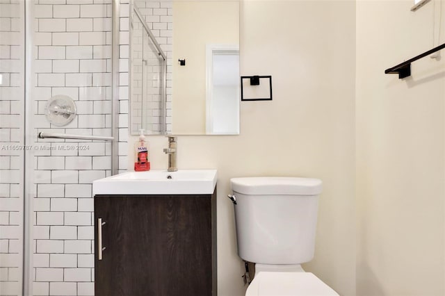 bathroom featuring a shower with shower door, toilet, and vanity