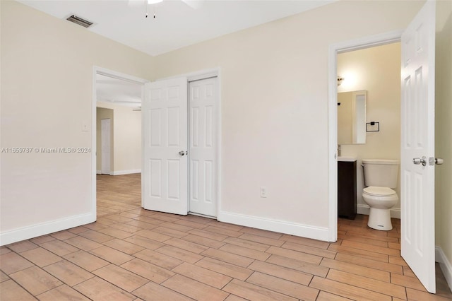 unfurnished bedroom featuring a closet, ceiling fan, connected bathroom, and light hardwood / wood-style flooring