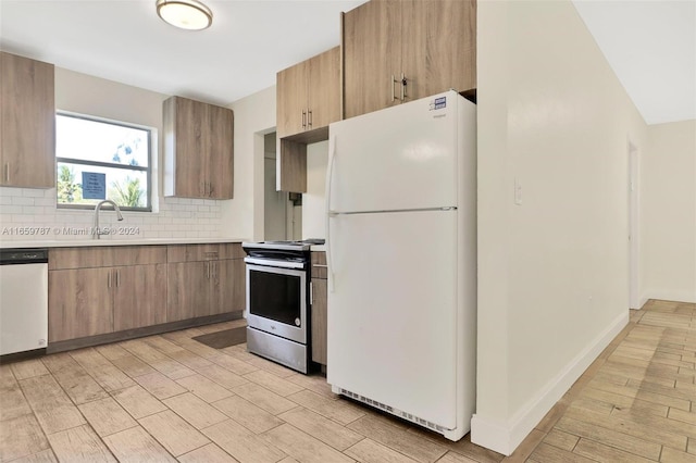 kitchen featuring stainless steel appliances, sink, decorative backsplash, and light hardwood / wood-style floors