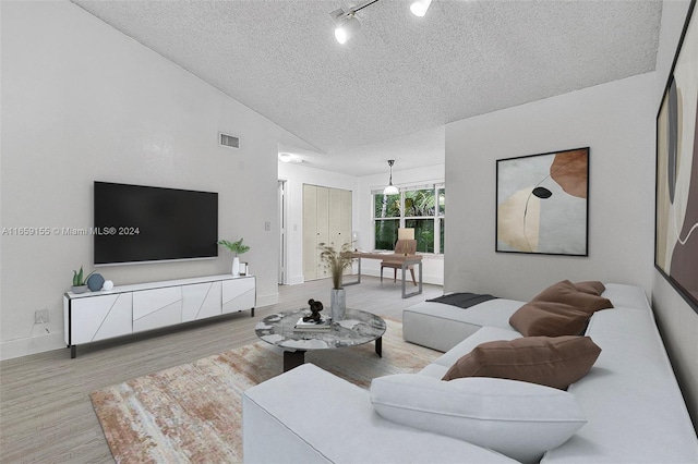 living room with lofted ceiling, a textured ceiling, and light hardwood / wood-style floors