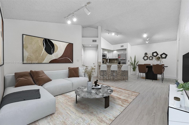 living room with rail lighting, high vaulted ceiling, a textured ceiling, and light hardwood / wood-style flooring