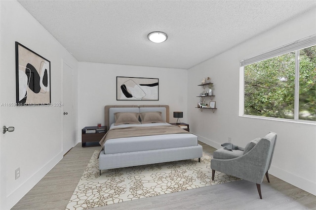 bedroom featuring a textured ceiling and light hardwood / wood-style floors