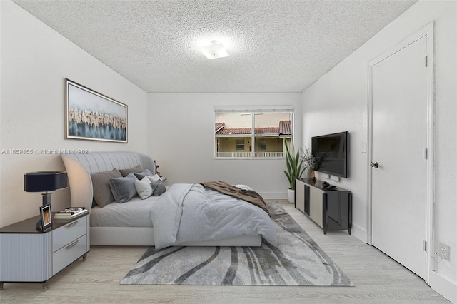 bedroom featuring light hardwood / wood-style flooring and a textured ceiling