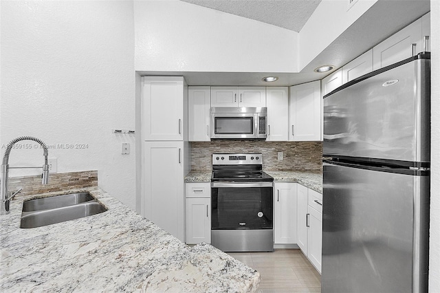 kitchen featuring appliances with stainless steel finishes, white cabinets, tasteful backsplash, and sink