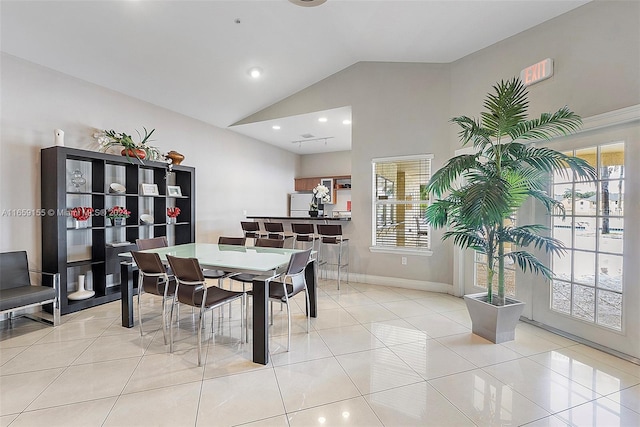 dining area featuring high vaulted ceiling, plenty of natural light, and light tile patterned floors