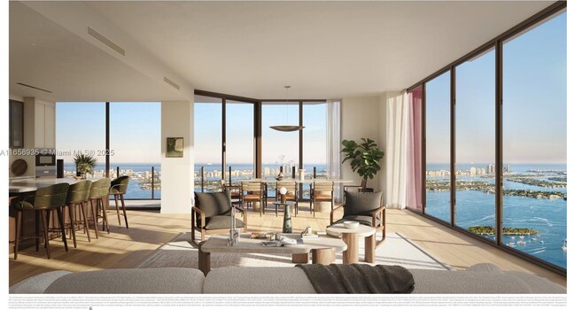 living room featuring light wood-type flooring, plenty of natural light, a water view, and expansive windows