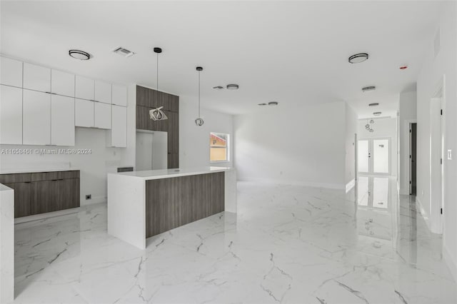 kitchen featuring hanging light fixtures, a center island, and white cabinetry