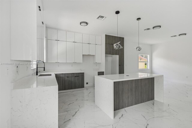 kitchen featuring white cabinetry, a center island, decorative light fixtures, and sink