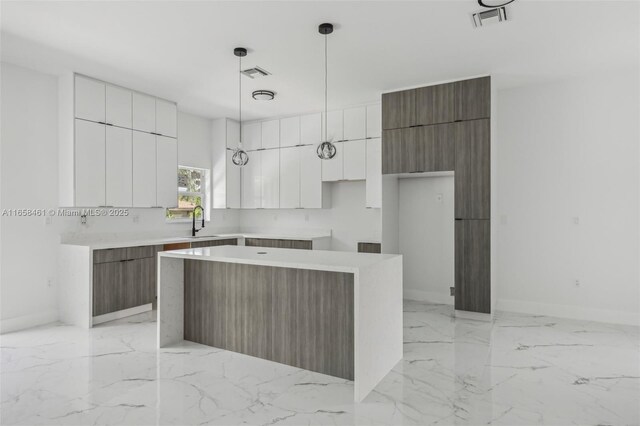 kitchen with pendant lighting, white cabinetry, a center island, and sink