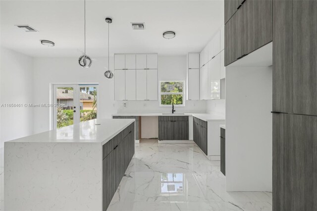 kitchen featuring a center island, pendant lighting, sink, and white cabinets