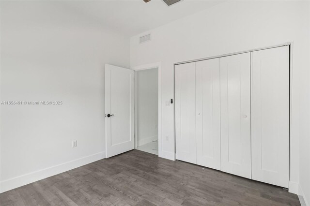 unfurnished bedroom featuring a closet and dark hardwood / wood-style floors