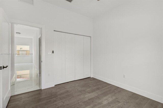 unfurnished bedroom with a closet and dark hardwood / wood-style floors