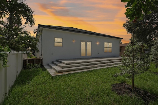 back house at dusk featuring a yard