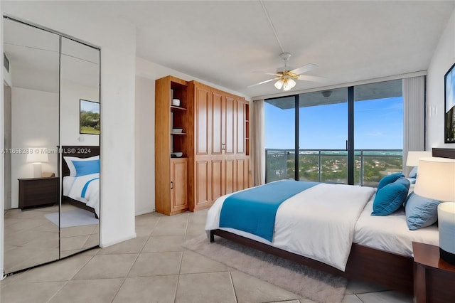 bedroom with expansive windows, ceiling fan, and light tile patterned flooring