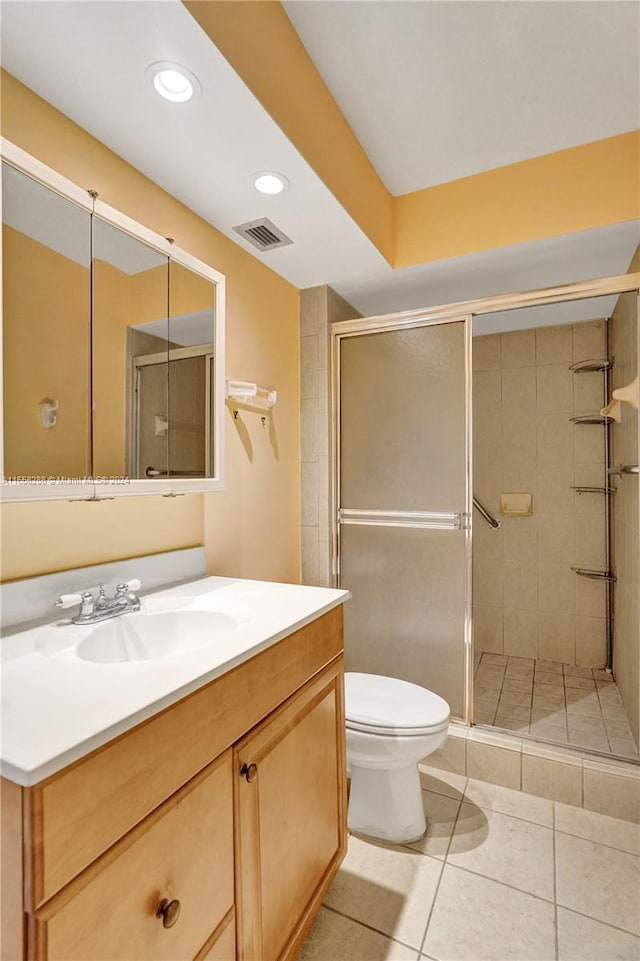 bathroom with tile patterned floors, vanity, a shower with shower door, and toilet