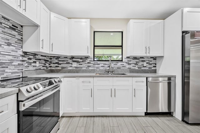 kitchen with stainless steel appliances, sink, light wood-type flooring, and white cabinetry