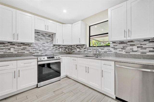 kitchen featuring light wood-type flooring, white cabinetry, tasteful backsplash, stainless steel appliances, and sink