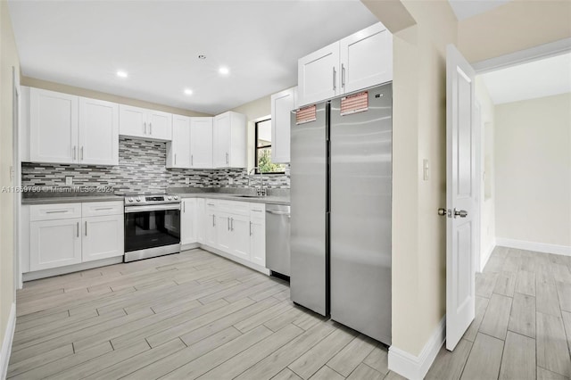 kitchen with white cabinets, light hardwood / wood-style flooring, appliances with stainless steel finishes, sink, and tasteful backsplash