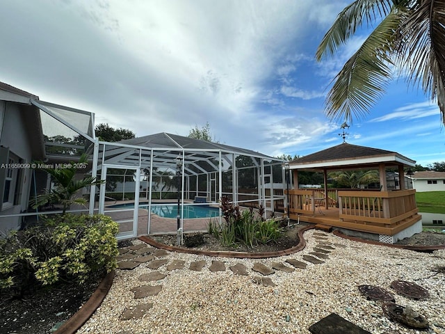 view of pool with a gazebo, a wooden deck, and glass enclosure