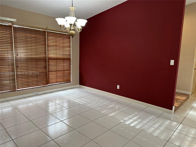 tiled empty room featuring a notable chandelier