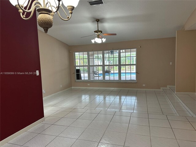 unfurnished room featuring vaulted ceiling, ceiling fan with notable chandelier, and light tile patterned floors