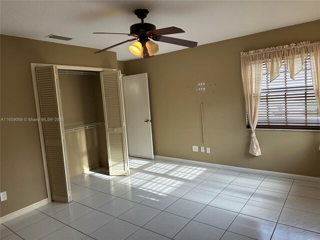 unfurnished bedroom featuring light tile patterned floors, a closet, and ceiling fan