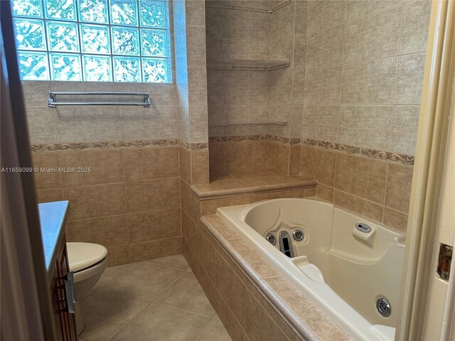 bathroom with tile patterned flooring, vanity, a relaxing tiled tub, and toilet