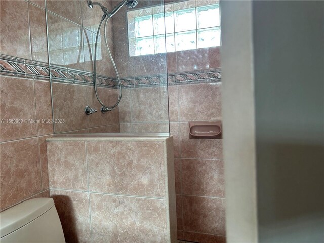 bathroom featuring toilet and tiled shower