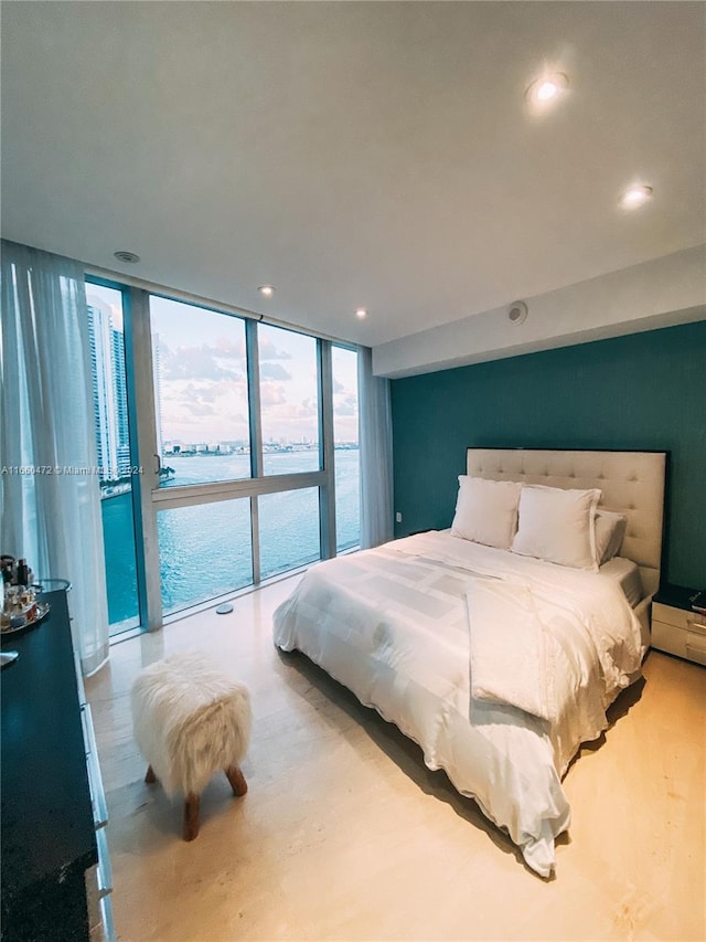 bedroom with a wall of windows, access to outside, a water view, and light hardwood / wood-style floors