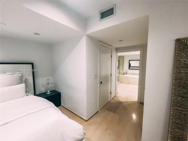 bedroom featuring light hardwood / wood-style flooring and connected bathroom