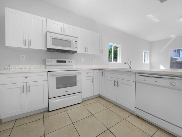 kitchen featuring white appliances, white cabinetry, sink, and light tile patterned floors