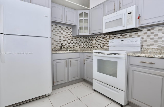 kitchen featuring backsplash, sink, light tile patterned floors, light stone counters, and white appliances