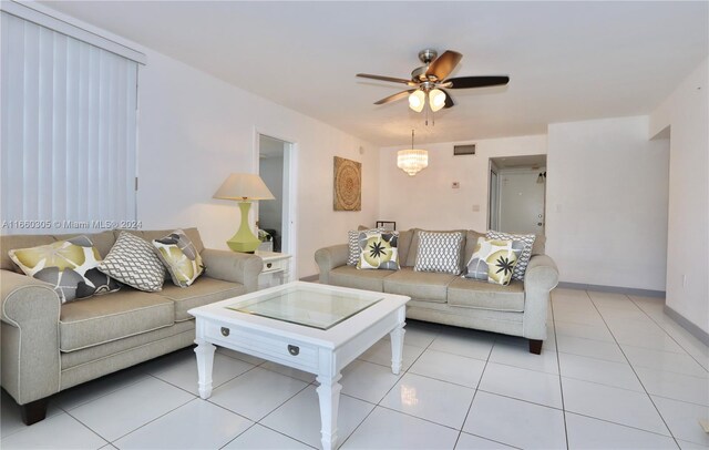 tiled living room with ceiling fan with notable chandelier