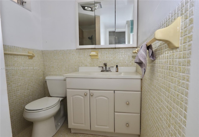 bathroom with vanity, toilet, and tile walls