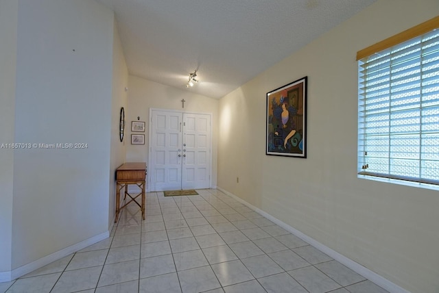 tiled entryway featuring lofted ceiling and a textured ceiling