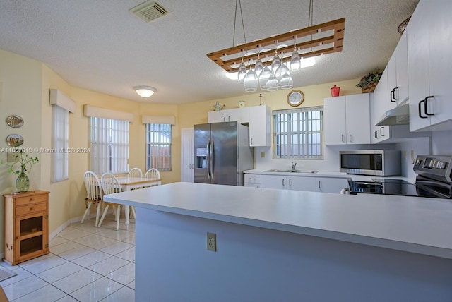 kitchen with decorative light fixtures, stainless steel appliances, white cabinetry, and a textured ceiling