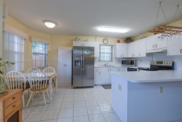 kitchen featuring light countertops, a peninsula, appliances with stainless steel finishes, under cabinet range hood, and a sink